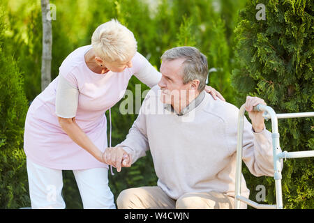 Portrait von Fürsorglichen Krankenschwester helfen älteren Menschen von parkbank in der Rehabilitation Center erhalten, kopieren Raum Stockfoto