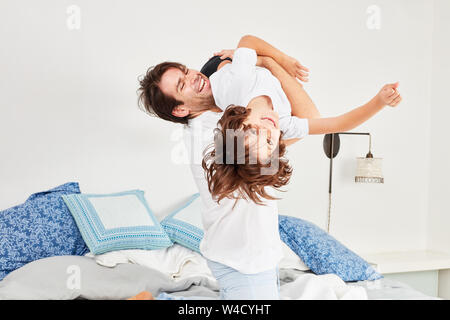 Vater und Sohn herumtollen und spielen miteinander im Bett im Schlafzimmer Stockfoto