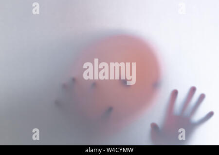 Halloween verschwommenen Hintergrund. Ein Geist wie ein Kürbis in Farbe hinter Glas. Schrecklich und schrecklichen Alptraum. Er klopft an, um das Fenster Stockfoto