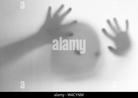 Halloween verschwommenen Hintergrund. Ein Geist wie ein Kürbis in Farbe hinter Glas. Schrecklich und schrecklichen Alptraum. Er klopft an, um das Fenster Stockfoto