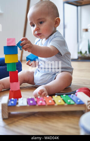 Mutter mit 8 Monat Baby Sohn Lernen durch Spielen mit farbigen Holzklötze zu Hause Stockfoto