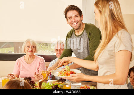 Glückliches Paar mit großeltern am Esstisch mit Mittag- oder Abendessen Stockfoto