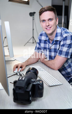 Portrait von männlichen Fotografen im Studio Bilder Sichten von Fotos auf dem Computer Stockfoto
