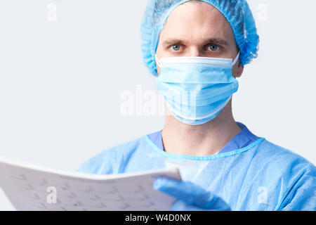 Studio Portrait von männlichen Chirurgen tragen Kleid und Maske Holding medizinischen Ausdrucken Stockfoto