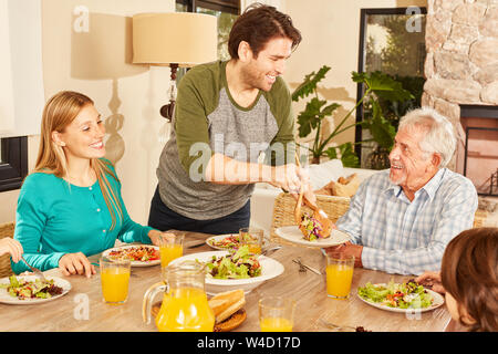 Glückliche Familie mit Großvater in Abend- oder Mittagessen im Innenbereich Stockfoto