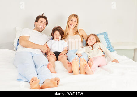 Glückliche Familie mit zwei Kindern entspannt auf das Bett im Schlafzimmer Stockfoto