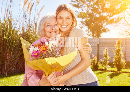 Erwachsene Tochter gibt Blumen zu Mutter am Muttertag Stockfoto