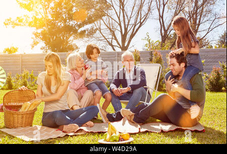 Familie mit Kindern und Großeltern feiert Geburtstag im Garten mit Picknick Stockfoto