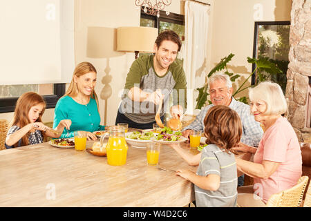 Erweiterte Familie mit Großeltern und Kindern beim Mittagessen in der Esstisch Stockfoto