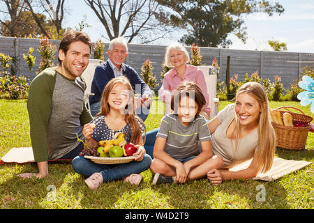 Familie mit Kindern und Großeltern feiert Geburtstag mit einem Picknick im Garten Stockfoto