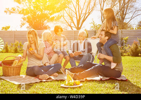 Erweiterte Familie mit Kindern und Großeltern mit Picknick im Garten im Sommer Stockfoto