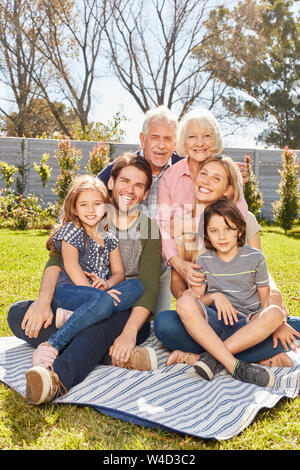 Drei Generationen einer Familie sind glücklich zusammen sitzen im Sommer im Garten Stockfoto