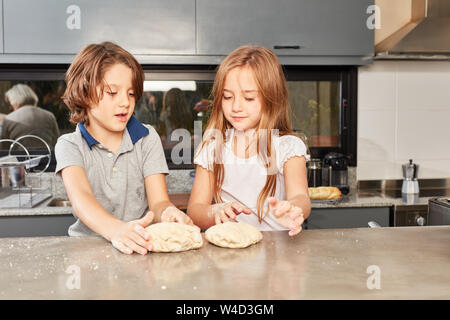 Zwei Geschwister Kinder kneten Teig zusammen in der Küche Stockfoto