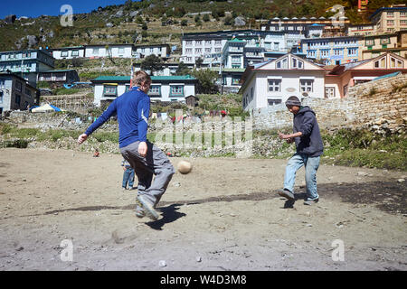 Namche Bazar, Nepal - Oktober 17, 2015: Unbekannte Kinder spielen Fußball auf staubigen Spielplatz, Namche Bazar Stockfoto