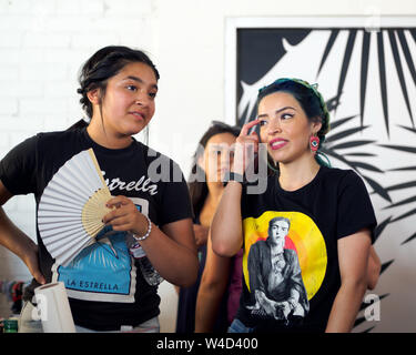 Zwei Latinas, einer Holding eine hand Ventilator, Gespräch an einem neuen "Loca für Lokale' Event in Corpus Christi, Texas USA. Stockfoto