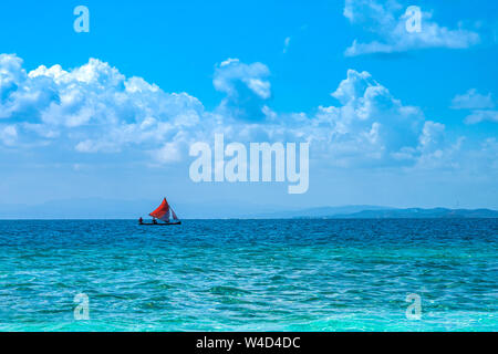 Guna Yala - San Blas kleine lokale Fischerboot mit Red Sail von türkisblauem Meer in der Karibik umgeben Stockfoto