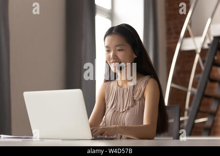 Lächelnd asiatischen Geschäftsfrau Rezeptionist das Headset funktioniert auf dem Laptop Stockfoto