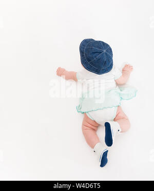 Crawling Baby auf weißem Hintergrund in Jeans Hut und Stiefeletten, Kleinkind Draufsicht, Neugeborenes Kind auf Decke Stockfoto