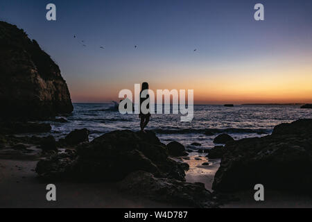 Frau, die auf einem Felsen, den Sonnenuntergang zu beobachten. Stockfoto
