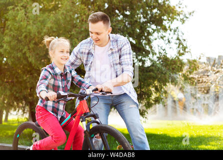 Kleine Mädchen lernen Radfahren mit ihrem Vati Stockfoto