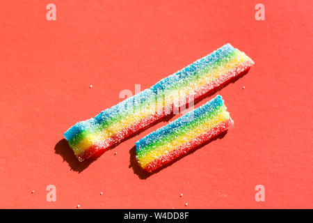 Farbige Marmelade in der Zucker auf dem roten Hintergrund. Natürliche regenbogenfarbenen Marmelade Süßigkeit. Platz kopieren, leere Vorlage für Text Stockfoto