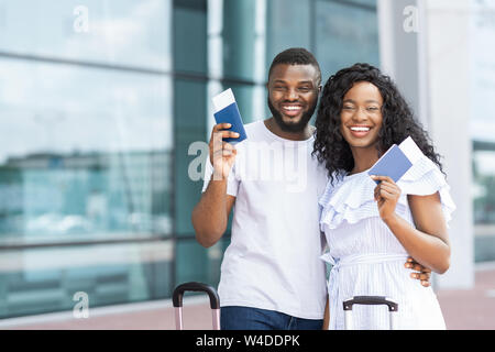 Afrikanische Paar lächelnd mit Flugtickets und Reisepass am Flughafen Stockfoto
