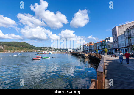 Menschen zu Fuß in der Avenida del Mar im Hafen mit kleinen Booten in Mugardos, Ria de Ferrol, Provinz A Coruña, Galicien, Spanien Stockfoto