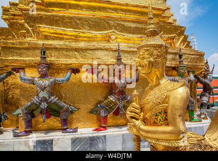 Garuda und Yaksha mythische Krieger Statuen bewachen die vergoldeten Chedi in der Nähe der Tempel des Smaragd Buddha im Grand Palace in Bangkok, Thailand. Stockfoto