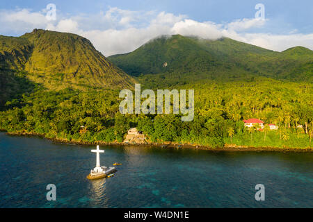 Luftaufnahme der goldenen Abendsonne leuchtenden ein großes Kreuz Kennzeichnung einer versunkenen Friedhof aus der vulkanischen tropischen Insel Camiguin Stockfoto