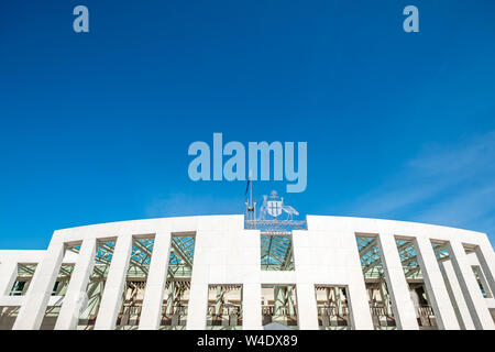 Unter einem blauen Himmel/kopieren, ist das strahlend weiße und Stahl Architektur von Australiens Parlament, Canberra, ACT, mit Emblemen, Schild und f Stockfoto