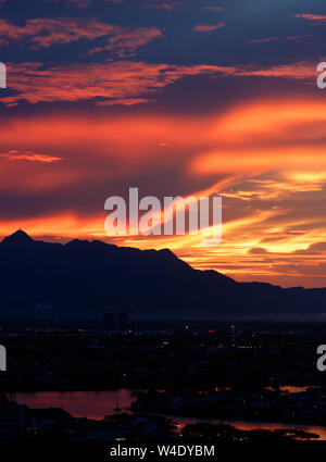 Brennende rote Himmel und Wolken über Guning Serapi Berge bei Sonnenuntergang in Kuching, Sarawak, Malaysia Stockfoto