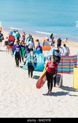 Eine Surf Instructor von den Fistral Beach Surf School führenden ihrer Klasse von Lernenden über Fistral Beach nach einer surflektion. Stockfoto