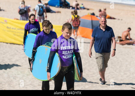 Junge Menschen bei der Rückkehr von einer surflektion mit Fistral Beach Surf Schule in Newquay in Cornwall. Stockfoto