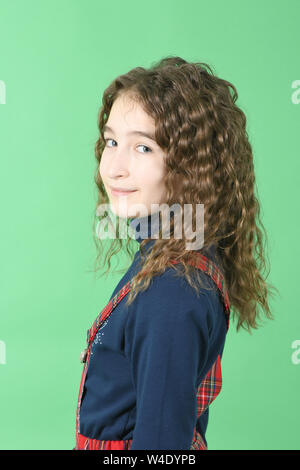 Portrait von adorable lächelnd Schulmädchen mit Haaren steht auf einem grünen Hintergrund isoliert Curl. Hochauflösendes Foto. Volle Tiefenschärfe. Stockfoto