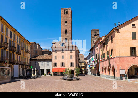 Gepflasterten Stadtplatz von typischen bunten Häusern und mittelalterliche Türme in Alba, Piemont, Norditalien umgeben. Stockfoto