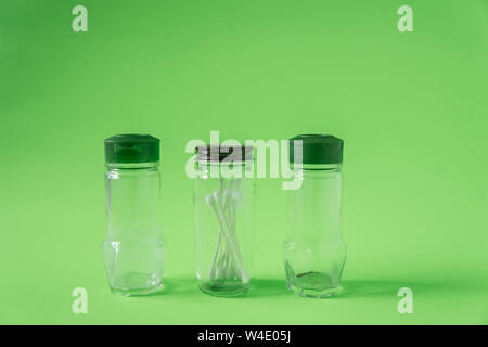 3 Glas Gewürzdosen auf Kalk grüner Hintergrund mit Leeren leeren Raum Platz für Text oder kopieren. Drei Flaschen recycelt und wiederverwendet Baumwolle sw zu speichern Stockfoto