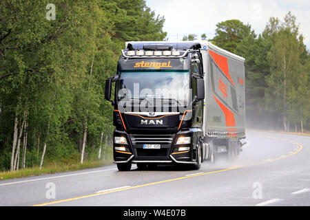 Raasepori, Finnland. Juli 5, 2019: Neue MAN TGX Truck von Stengel LT mit hellen Scheinwerfer hols Trailer zusammen finnische Nationalstraße 25 an einem regnerischen Tag. Stockfoto