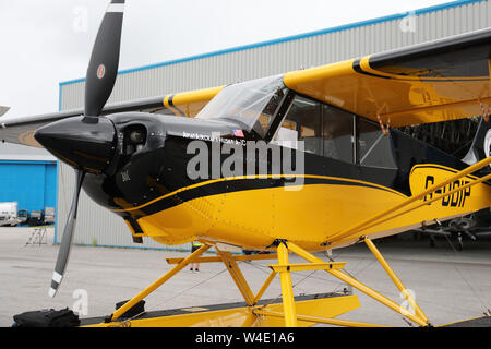 Eine gelbe Beagle Husky A-1 C durch den Hangar am Aviation Park, Hawarden Airport, Chester, UK geparkt Stockfoto