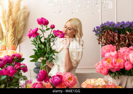 Schöne blonde Frau nimmt florist Blumen und erzeugt wunderbare Bouquet Stockfoto