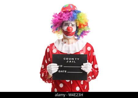 Trauriger Clown mit einem Gefängnis Board auf weißem Hintergrund posiert Stockfoto