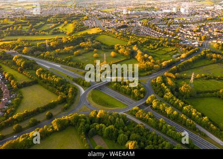 Luftbild mit Blick auf eine typisch britische Autobahnkreuz. Atemberaubenden Sonnenuntergang Licht gibt den nahe gelegenen Bäume, Felder und Häuser, die wunderschöne goldene g Stockfoto