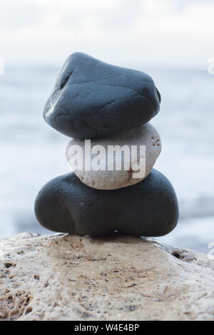 Eine kleine Sammlung von Felsen am Strand mit dem Meer im Hintergrund gestapelt Stockfoto