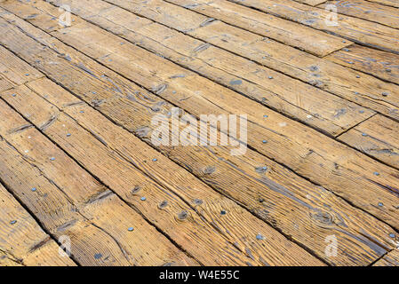 Alte hölzerne Pier Planken mit Rissen und Nägel. Board sind diagonal, mittel braun. Stockfoto