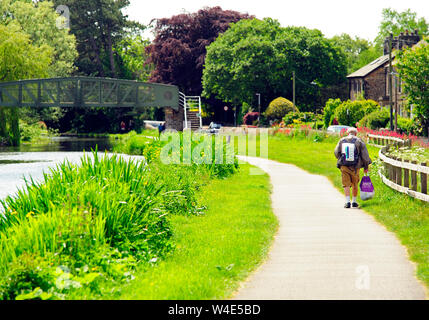 Ansicht der Rückseite des älteren Mann mit Rucksack und Kunststoff Warenkorb wandern entlang der Lancaster Canal im Frühjahr Stockfoto