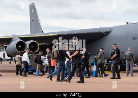 Bewaffnete Polizisten patrouillieren im Royal International Air Tattoo Airshow, RAF Fairford, Cotswolds, UK. Boeing B-52 Stratofortress nukleare Bomber Flugzeug Stockfoto