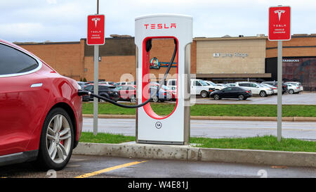 Red Tesla Model S Plug-in zu Tesla Kompressor ausgeht, mit Tesla Fahrzeug Laden neben an CF Limeridge in Hamilton, Ontario. Stockfoto