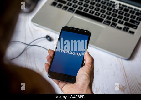 Nizhyn, Ukraine/Juli -16-2019: Junge schöne Mädchen halten Smartphone mit Facebook App gestartet. Social media Konzept. Stockfoto