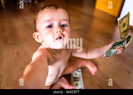 Baby erreichen einige Dollarscheine, verschwendet Familie Einsparungen Konzept Stockfoto