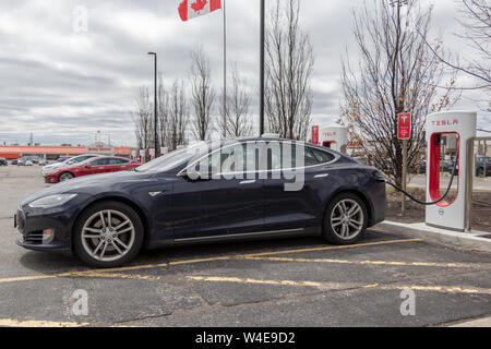 Blau Tesla Model S bei Tesla Kompressor in Markham, mit Model S, Modell X und Kanadischen Flagge im Hintergrund geparkt. Stockfoto