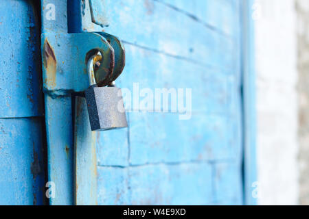 Alte Schloss auf einem blauen Metalltür mit Holzbohlen Risse im Lack und Rost Stockfoto